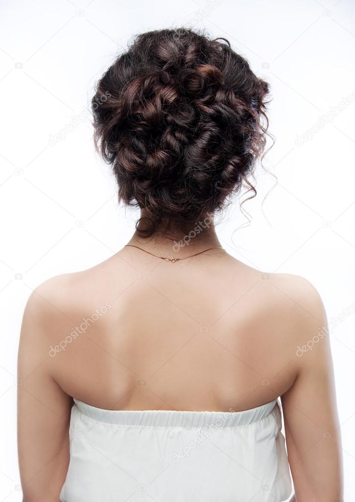 Brunette with an evening hairstyle. View from the back.