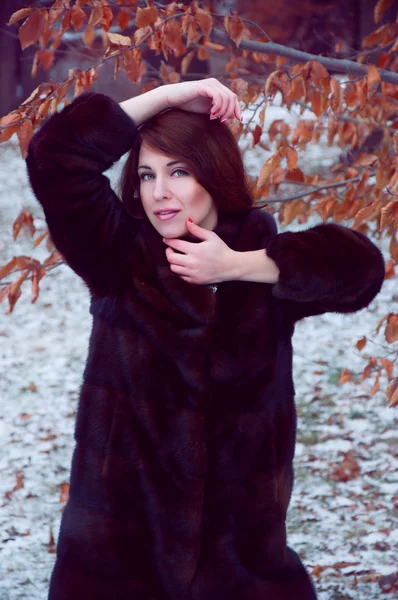 Outdoor portrait of beautiful smiling redheaded woman in fur coa