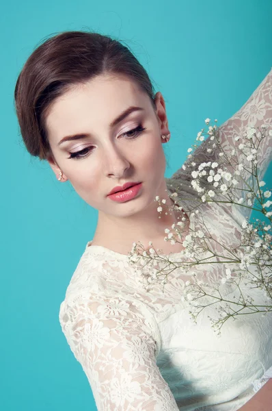 Mooie vrouw in witte jurk op turkooizen achtergrond — Stockfoto