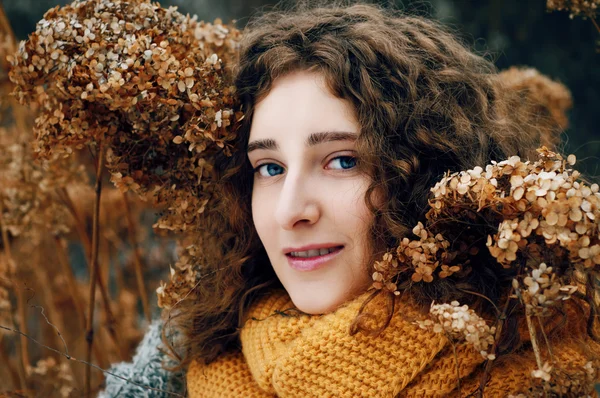 Atractiva mujer joven con el pelo rizado cerca de flujo de hortensias secas Imagen de archivo