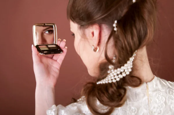 Young woman looking into a small mirror — Stock Photo, Image