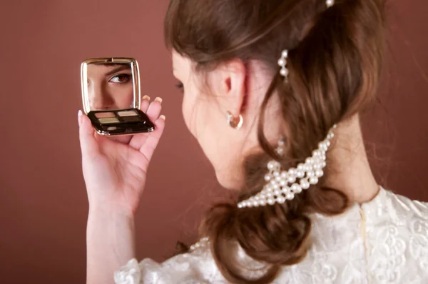 Young woman looking into a small mirror Stock Picture