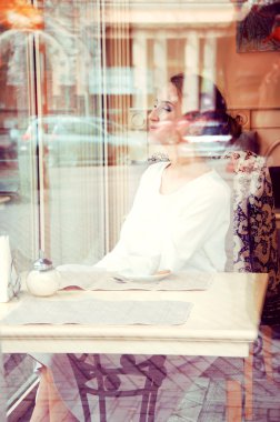 Güzel zarif sarışın çay içme bir kafede oturuyor. Görünüm thr