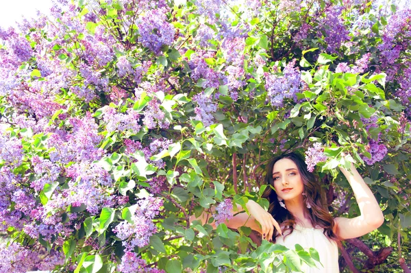 Woman with long brown hair in lilac bushes — Stock Photo, Image