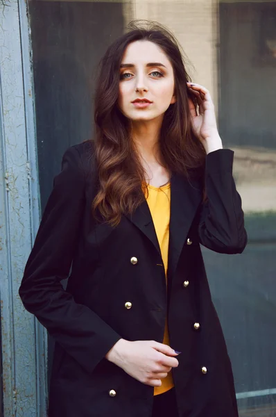 Young woman portrait in black trenchcoat and yellow blouse