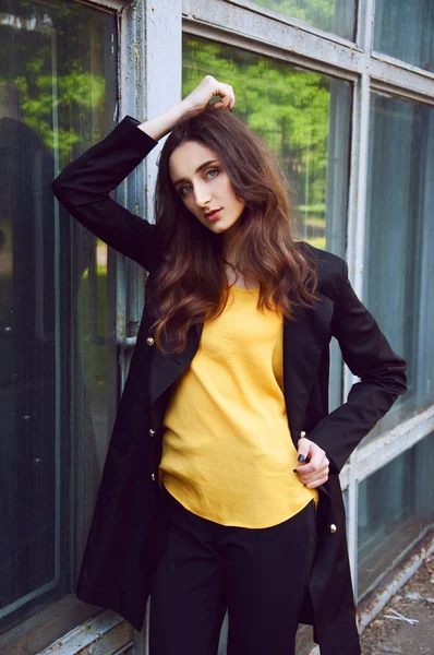 Junges Frauenporträt in schwarzem Trenchcoat und gelber Bluse — Stockfoto