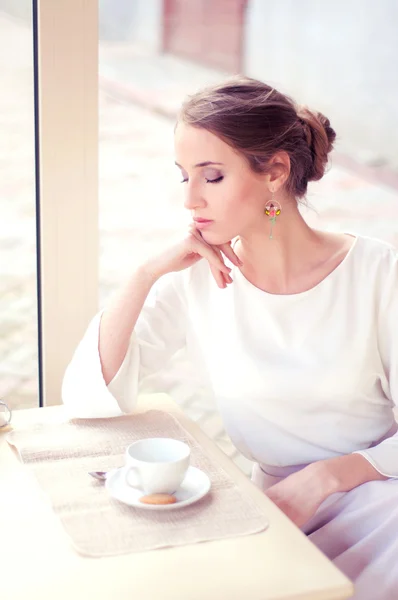 Hermosa rubia elegante sentada en un café bebiendo té Imágenes de stock libres de derechos