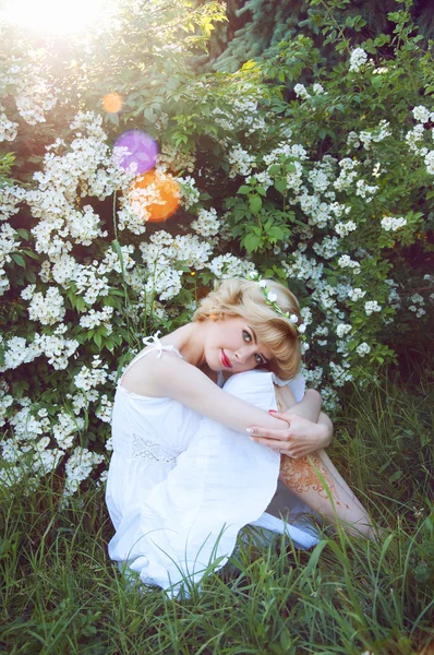 Mulher loira bonita em sundress branco sentado na grama ne — Fotografia de Stock