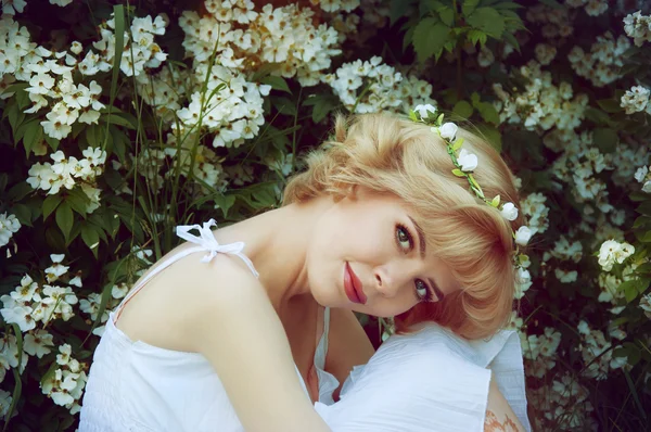 Beautiful blonde woman in white sundress sitting on the grass ne — Stock Photo, Image