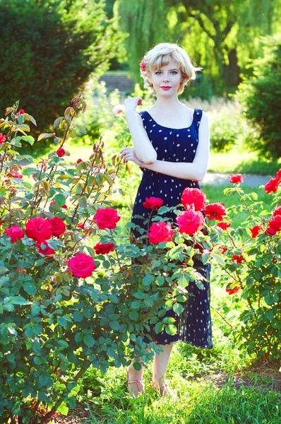 Hermosa mujer rubia en vestido azul posando en el jardín —  Fotos de Stock