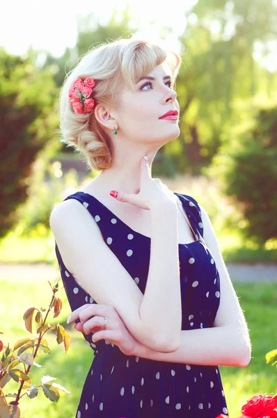 Vacker blond kvinna i blå klänning poserar i trädgården — Stockfoto
