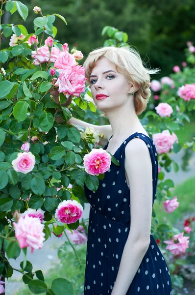 青いドレスの庭でポーズの金髪美人 — ストック写真