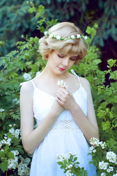 Hermosa mujer rubia en vestido blanco posando en el jardín Fotos de stock