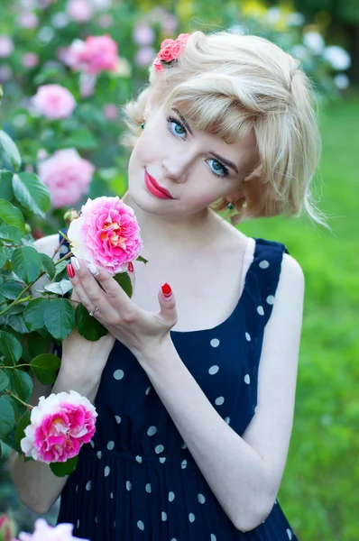 Hermosa mujer rubia en vestido azul posando en el jardín Imagen de archivo