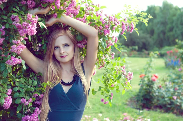 Blonde kaukasische Frau sitzt auf dem Gras im Rosenkranzgarten — Stockfoto