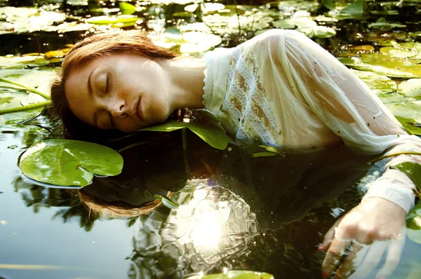 Inschrijving jonge vrouw zwemmen in de vijver onder water lelies — Stockfoto