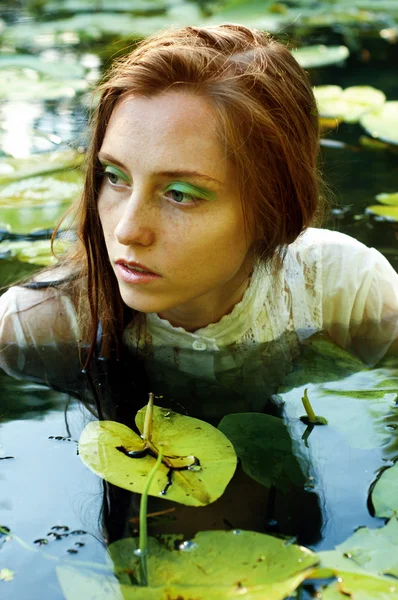 Inschrijving jonge vrouw zwemmen in de vijver onder water lelies — Stockfoto