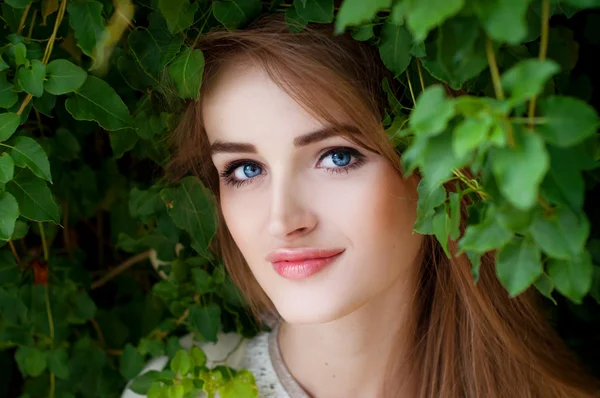 Happy smiling beautiful young woman surrounded by green leaves — Stock Photo, Image