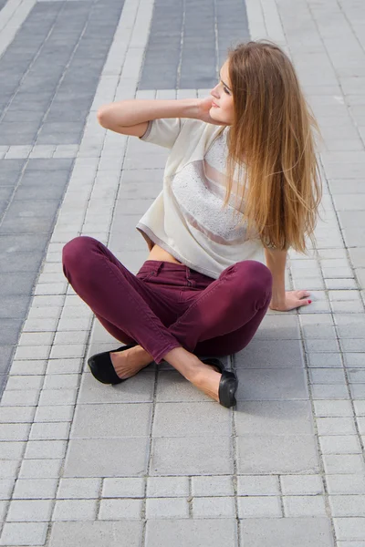 Nettes blondes Mädchen mit langen Haaren sitzt auf dem Boden — Stockfoto