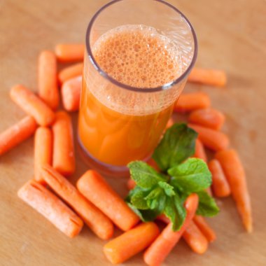 Küçük soyulmuş havuç ve nane ile bir bardak havuç suyu