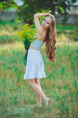 Doğada bir buket kır çiçeğiyle güzel bir kız.