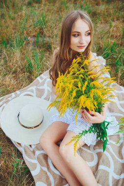 Doğada bir buket kır çiçeğiyle güzel bir kız.