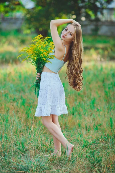 Doğada bir buket kır çiçeğiyle güzel bir kız.