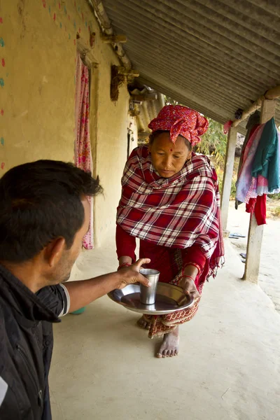Tharu mulher oferecendo chá em nepali terai — Fotografia de Stock