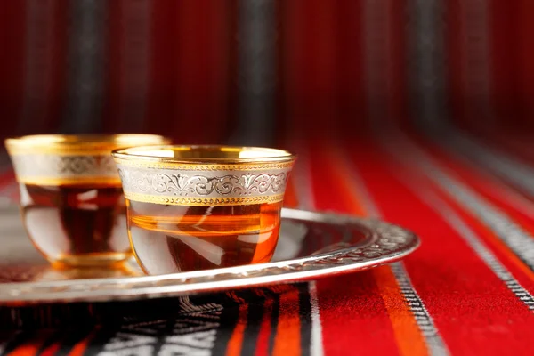 Una bandeja de tazas de té árabe se coloca en tela tejida árabe — Foto de Stock