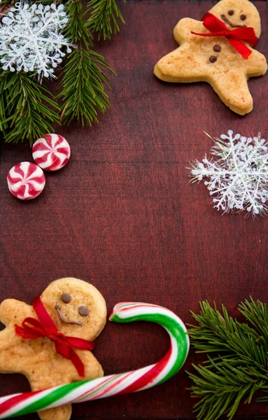 Weihnachten Hintergrund mit Lebkuchen, Bonbons, Tannenzweige auf dem alten Holzbrett — Stockfoto
