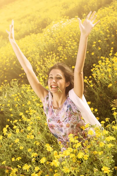 Gelukkig dolgelukkig meisje in een veld van de bloem — Stockfoto