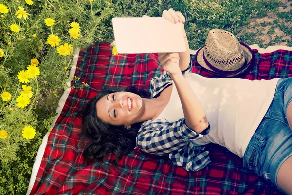 Happy girl reading a tablet on a blanket — Stock Photo, Image
