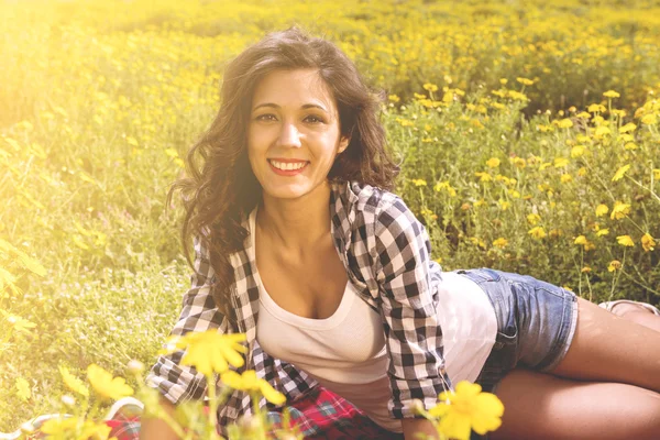 Heureuse fille souriant dans un champ de fleurs — Photo