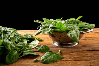 Eski ahşap bir masa üzerinde kevaşede taze ıspanak.