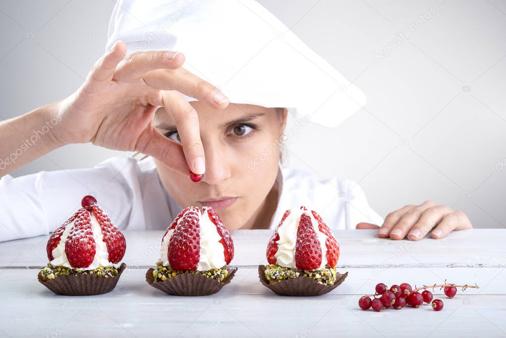 woman pastry chef decorates small strawberry cakes