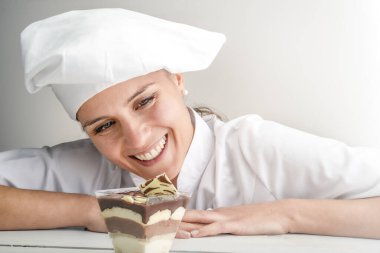 Tiramisu yerken gülümseyen kadın pasta şefi, tipik bir Sicilya tatlısı.