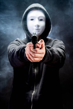 Suç hırsızı, siyah arka planda korku ve tehlike savunması kavramına silah doğrultuyor