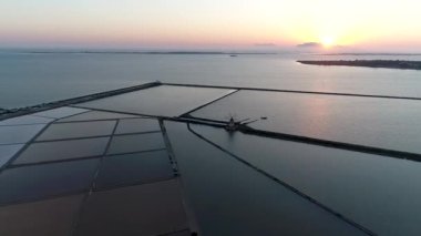 Sicilya 'da Trapani' nin tuzlu tavalarının hava manzarası. Gün batımında denizin üzerinde, arkasında da Cynthia adası var.
