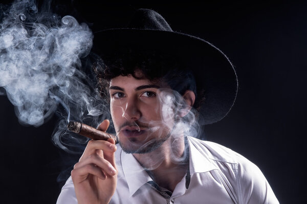 Handsome man holding cigar with smoke