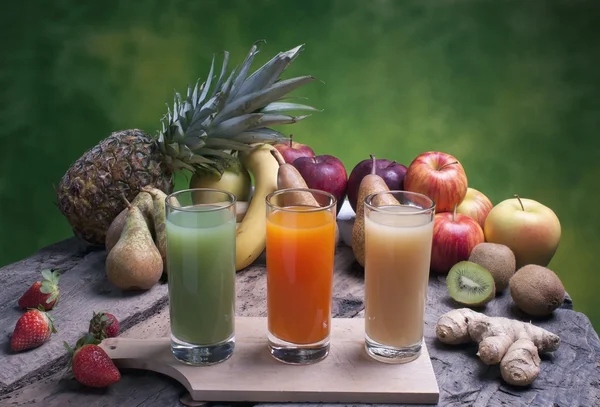 Fruits mélangés sur une planche de bois avec du jus — Photo