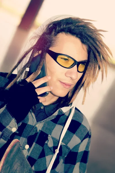 Portrait of young guy  with rasta hair talking phone warm filter — Stock Photo, Image