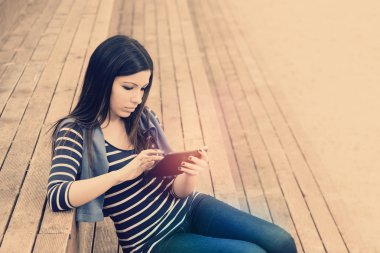 Merdivenleri sıcak filtre uygulaması üzerinde oturan tablet ile güzel esmer kız