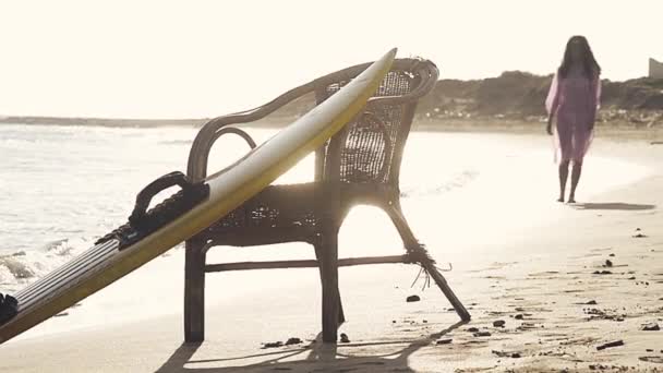 Focus sélectif sur la planche de surf sur la plage avec une fille à pied defocus — Video