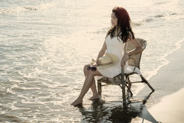 Deniz kenarında bir sandalyede oturan kız — Stok fotoğraf