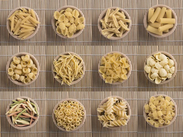 Vari tipi di pasta cruda in una ciotola di legno — Foto Stock