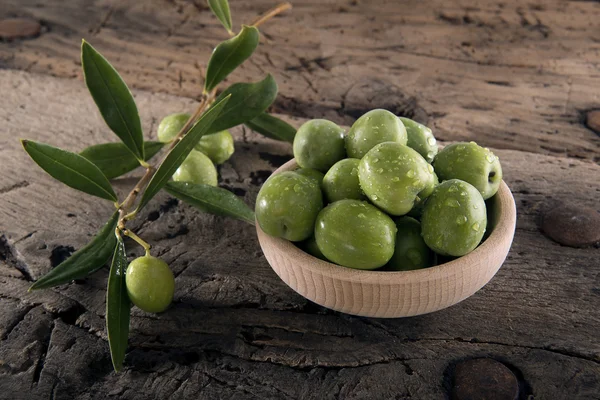 Olives into wood pot on an old wooden table — Stock Photo, Image