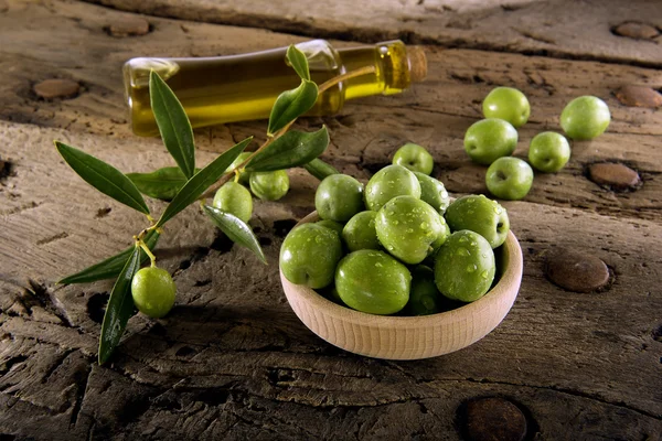 Oliven und Flaschenöl auf einem alten Holztisch — Stockfoto