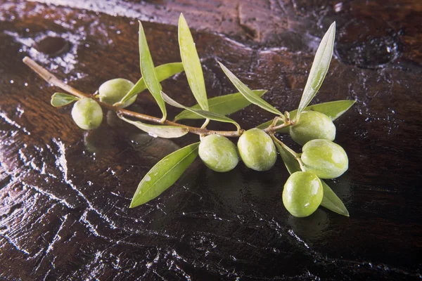Branch of olive on a old wodden table — Stock Photo, Image