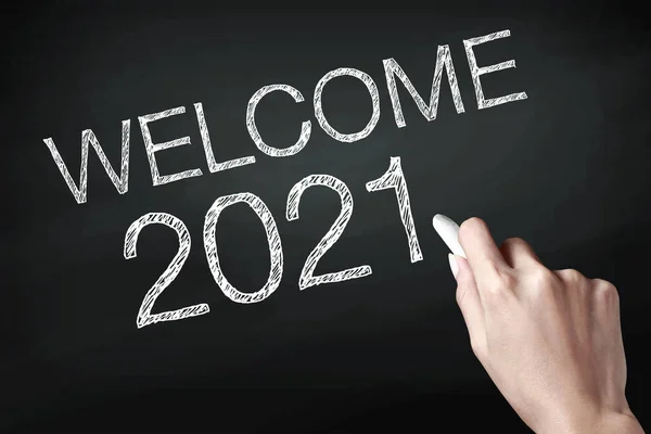 Hand holding a chalk and writing welcome 2021, wish you all the best as always in this coming new year