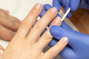 Güzellik salonunda bambu çubuğu kullanarak manikür yapmak. Manikürcü, manikürcü, bakım, parmak, alet, işlem, tırnak cilası